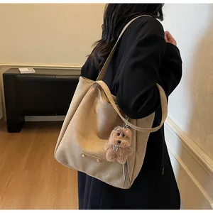 Close-up of soft khaki suede tote bag with cute brown plush puppy charm on handle