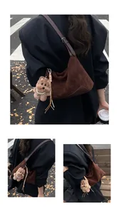 Detail of dark brown faux suede hobo bag featuring a plush puppy charm with pearl necklace