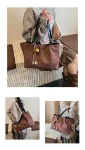 Detail of laser-cut floral patterns on brown suede tote bag with ethnic tassel charm