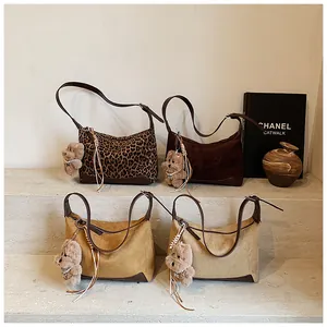Detailed view of suede faux leopard print and solid color retro shoulder bags with bear charms