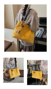 Detail of yellow hollow flower pattern faux suede tote bag with decorative tassel charm