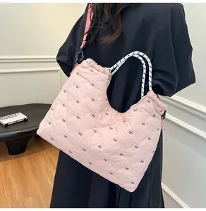 Detail van roze gewatteerde shopper met strikborduursel en gevlochten hengsels