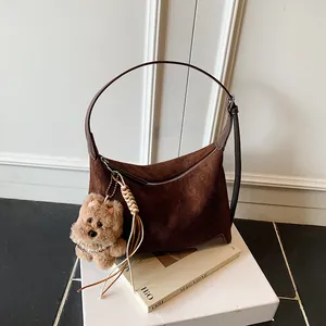 Deep brown suede hobo bag with a plush bear pendant and long leather shoulder strap