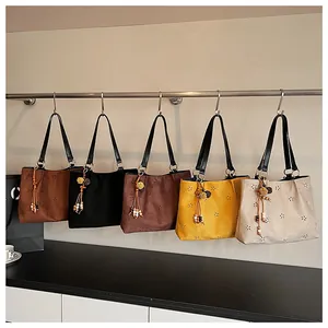 Detail of laser-cut floral patterns and colorful tassel charms on suede tote bags