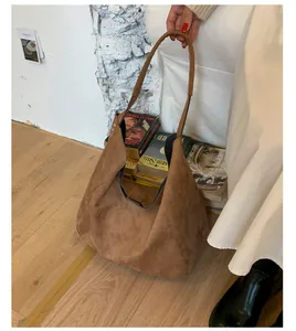 Detail view of large brown suede hobo bag with slouchy drape and wide shoulder strap