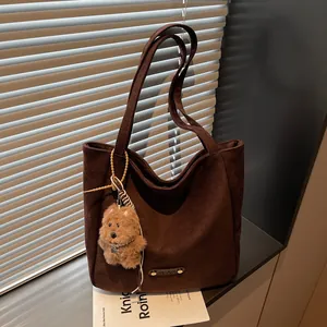 Vintage brown suede tote bag with cute plush bear charm in soft natural window light