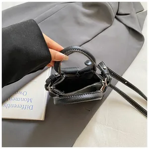 Mini black pebbled leather tote bag with white stitching and crossbody strap