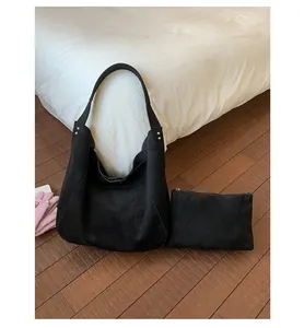 Detail of black suede hobo bag and matching pouch with metallic stud accents