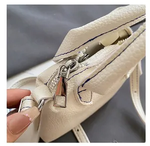 Detail of white lychee leather texture with silver zipper and blue contrast stitching
