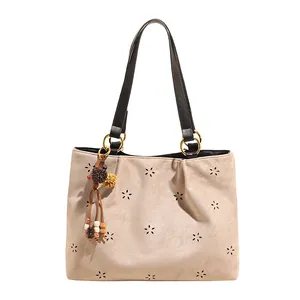 Minimalist beige suede tote bag with laser-cut floral patterns and ethnic charm