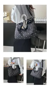 Detail van zwarte gewatteerde shopper met witte strikborduursels en geweven handvatten
