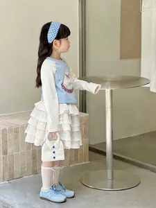 Detail of light blue long-sleeve top with plush animal applique and layered lace skirt