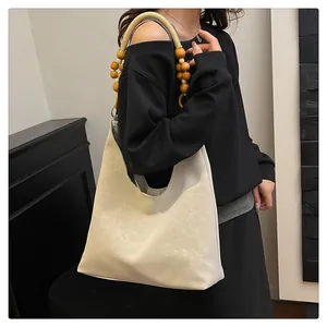 Détail du sac hobo avec anse en perles de bois et cuir beige à texture vintage