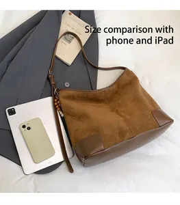 Detail van suède draagtas met grote capaciteit voor iPad en telefoon op een grijze blazer