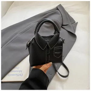 Detail of black mini handbag featuring a creative blazer collar design and white stitching
