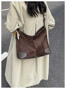 Detail van donkerbruine suède shopper met kleurrijke houten kralen tegen een straatachtergrond