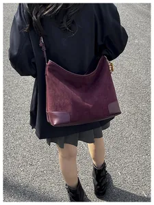 Gedetailleerd zicht op de grote bordeauxrode suède hobo tas met lederen bies bij een model