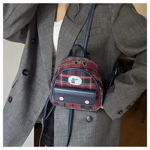 Detail of vintage red and black plaid mini backpack with bear patch and leather straps