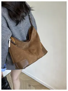 Detailopname van bruine suède hobo tas met houten kralen en lederen hoekaccenten