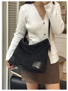 Detail van zwarte suède hobo tas met brede riem en houten kralen op het model