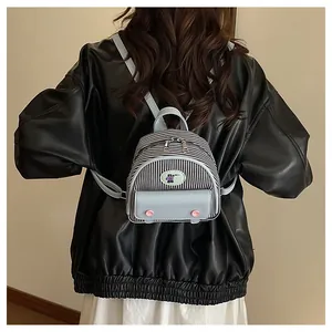 Rear view of model wearing a mini black and white striped backpack with blue bear patch