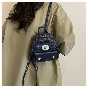 Navy blue plaid mini backpack on model back showing compact size and school style