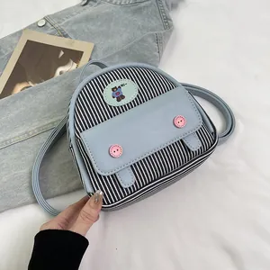 Detail of mini backpack with black white stripes, light blue flap and pink buttons