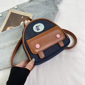 Detail of blue denim mini backpack with brown leather flap and cute bear patch decoration