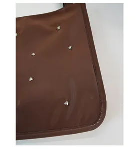 Detail of dark brown tote bag featuring silver heart rivets and scratch-resistant fabric