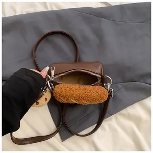Brown leather crossbody bag with silver hardware and a plush charm shown from above