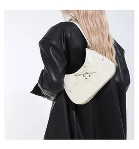 Detail of cream white glossy underarm bag with bow decoration and silver studs