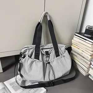 Detail der hellgrauen Nylon-Reisetasche mit Kordelzugtasche auf minimalistischem Grund