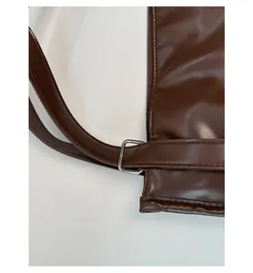 Detail of brown leather tote bag showing reinforced stitching and metal strap attachment