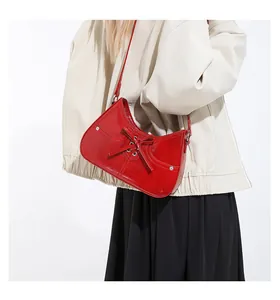 Red shoulder bag with bow tie and metallic studs shown on model in a minimalist style