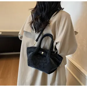 Vue détaillée du sac à main noir mat porté par un mannequin avec boucle dorée chic