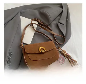 Detail showing brown suede shoulder bag with horseshoe buckle and leopard bear charm
