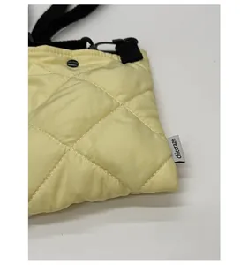 Gros plan d'un sac bouffant matelassé jaune pâle avec texture soyeuse et bandoulière noire