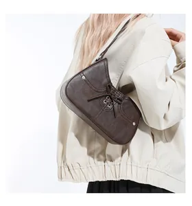 Detail of dark brown underarm bag featuring trendy lacing design and metal eyelets