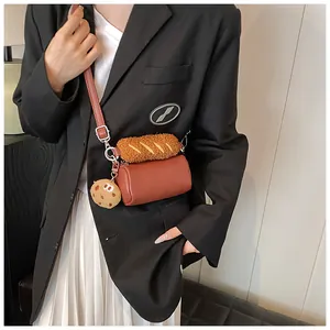 Detail of creative brown cylinder bag with plush baguette and cookie charm on a model