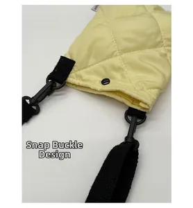 Détail du tissu matelassé jaune avec fermeture à pression et bandoulière tissée noire