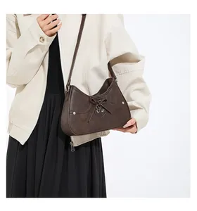 Detail view of dark brown semi-moon baguette bag with bow and silver studs on the model