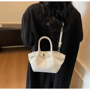 Sac hobo en cuir blanc avec plis latéraux et boucle en métal porté par un mannequin