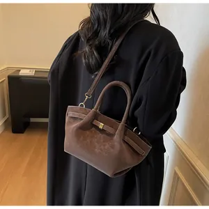 Détail du sac bandoulière en daim marron foncé montrant la texture vintage et la sangle
