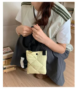 Gros plan du sac seau matelassé jaune avec un pendentif pingouin et fermoir à pression