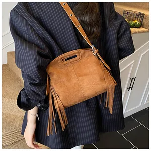 Close-up of caramel suede handbag with long tassels and adjustable eyelet shoulder strap