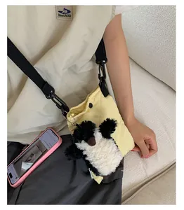 Gros plan sur le sac seau matelassé jaune avec pendentif pingouin et bandoulière noire