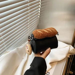 Mini black cylinder crossbody bag with brown plush bread charm and biscuit pendant