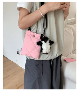 Détail du sac matelassé rose en nylon avec charme de pingouin et bandoulière fine
