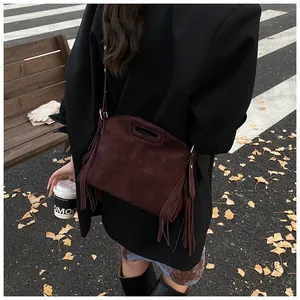 Detail of dark brown suede shoulder bag with side tassels and bohemian retro style