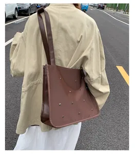 Detail of dark brown tote bag with silver studs and double straps for daily commute